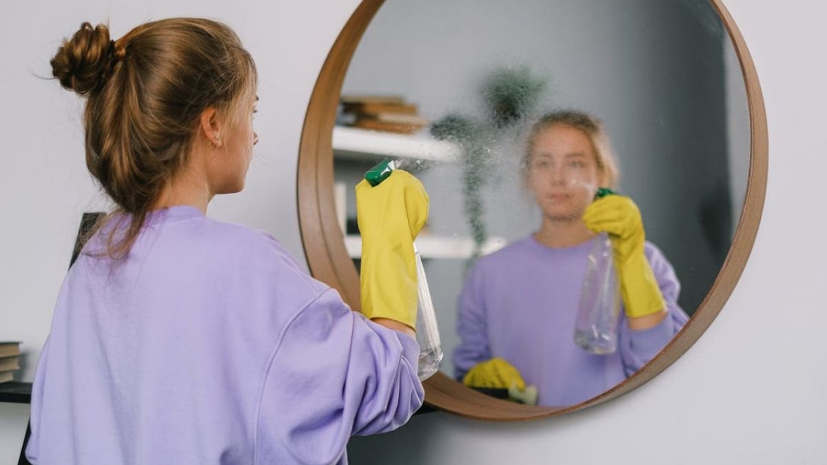 mulher limpando espelho de parede